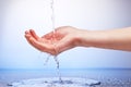 Water falling in womanÃ¢â¬â¢s hand on white and blue Royalty Free Stock Photo